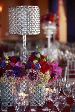 Elegant floral centerpieces with deep purple and pink flowers in crystal vases.
