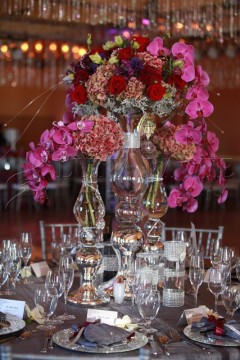 Elegant floral centerpiece with vibrant pink and red flowers on a glass table.