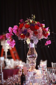 Elegant floral centerpiece with vibrant pink and red flowers in a clear vase.