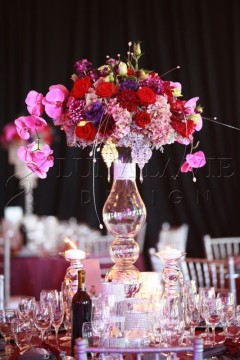 Elegant floral centerpiece with vibrant pink and red flowers in a tall glass vase.