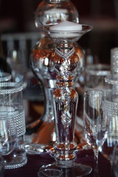 Elegant silver pitcher surrounded by crystal glasses on a reflective surface.