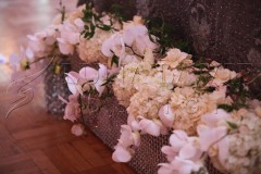 Elegant floral arrangement with white orchids and cream hydrangeas in a rustic container.
