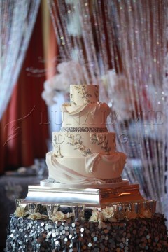 Elegant white wedding cake with intricate floral and bird details.
