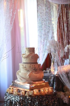 Elegant three-tier wedding cake with floral decorations and soft lighting.