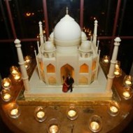 A detailed miniature model of the Taj Mahal surrounded by small candles.