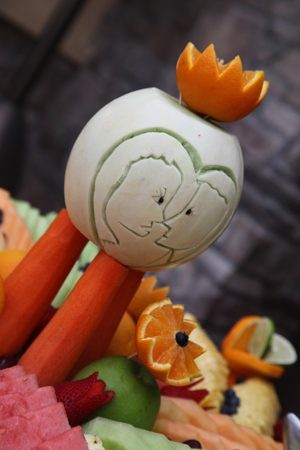 Carved white pumpkin with a face and orange fruit decoration.