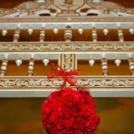 A red floral ball hangs from a white ornate railing.