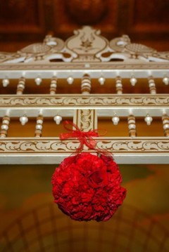 A red floral ball hangs from a white ornate railing.
