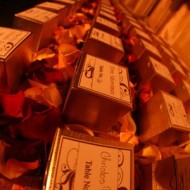 Rows of wedding favor boxes with thank you notes and rose petals.