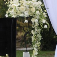 Elegant white floral arrangement cascading down a stand at an outdoor event.