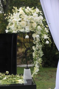 Elegant white floral arrangement cascading down a stand at an outdoor event.
