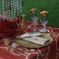 Elegant table setting with red roses and gold-rimmed glassware.