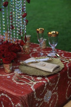 Elegant table setting with red roses and gold-rimmed glassware.