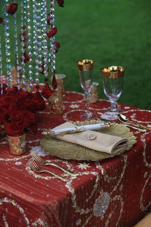 Elegant table setting with red roses and gold-rimmed glassware.