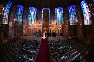 A couple exchanging vows in a grand, ornately decorated church filled with guests.