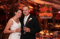 A smiling bride and groom holding drinks at their wedding reception.