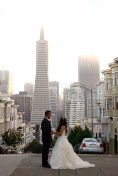 Couple holding hands on a city street with skyscrapers in the background.