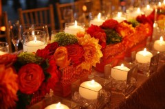 Elegant floral centerpiece with roses and candles on a table.