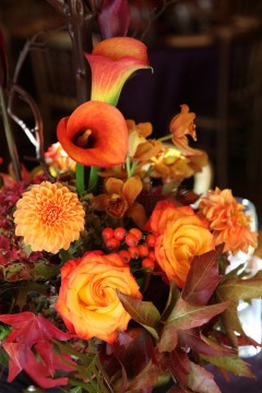 A vibrant autumn bouquet with orange roses and berries.