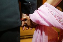 An elderly couple holding hands, showing care and connection.