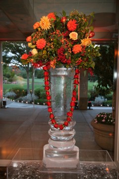 Elegant floral arrangement in a clear glass vase with vibrant red and orange flowers.