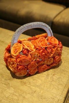 A handbag covered entirely with vibrant orange roses.