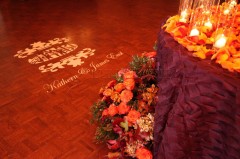 Elegant wedding stage with floral decorations and personalized floor design.