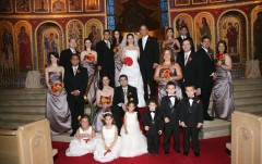 Large wedding party posing in a church with ornate decorations.