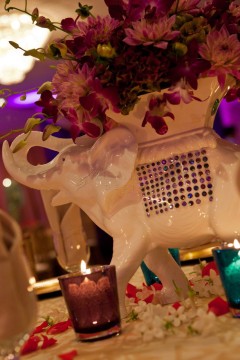 Decorative white elephant figurine with purple orchids and colorful candles.