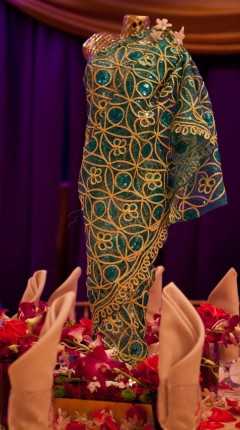 Close-up of intricate green and gold embroidered fabric on a garment.
