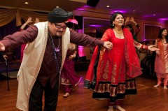 A joyful couple dancing at a festive event, dressed in traditional attire.