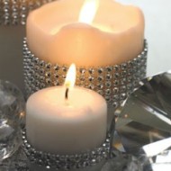 Two elegant candles with rhinestone holders, one lit, creating a warm ambiance.