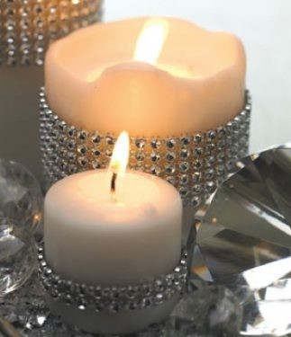 Two elegant candles with rhinestone holders, one lit, creating a warm ambiance.