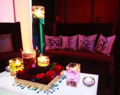 Romantic candlelit setting with rose petals and cushions.