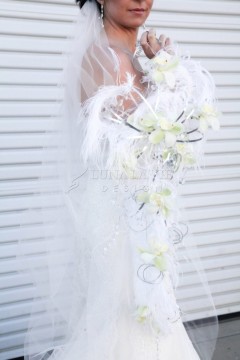 Bride holding a delicate bouquet of white flowers with veil and lace details.