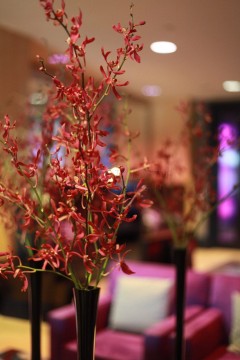 Close-up of red floral centerpiece on a table in a softly lit room.
