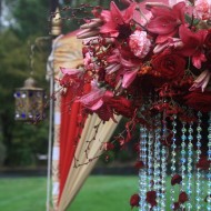 Intricate pink flowers with hanging bead decorations at an outdoor event.