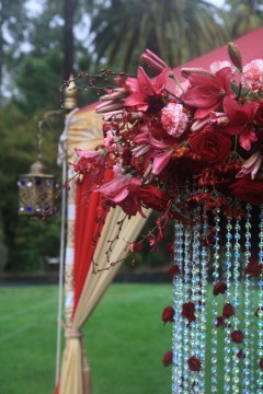 Intricate pink flowers with hanging bead decorations at an outdoor event.