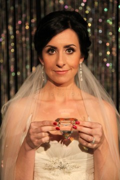 Bride in a veil holding a ring box, smiling softly.