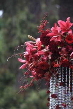 A close-up of a deep red floral arrangement with hanging crystal beads.