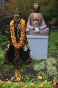 Statue adorned with marigold garlands in a serene garden setting.