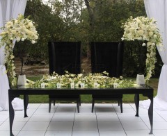 Elegant black and white floral arrangement on a sleek black table outdoors.