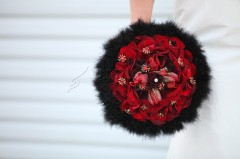 Elegant black and red floral bouquet with feather accents.