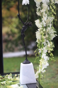 Elegant black sculpture with cascading white flowers on a white base.