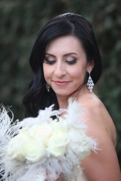 A woman with dark hair smiles softly, holding a white bouquet.