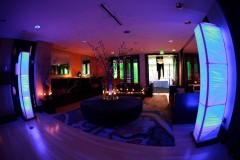 Modern lounge with ambient purple and orange lighting and sleek furniture.