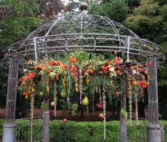 A decorative metal gazebo adorned with hanging orange and green floral arrangements.
