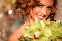 Smiling woman with curly red hair holding a bouquet.