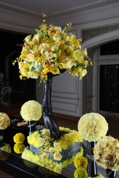Elegant floral arrangement with yellow flowers in a black vase.