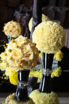 Elegant yellow floral spheres on black stands as centerpiece decor.